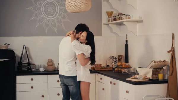 Mulher feliz na camisa branca abraçando namorado na cozinha moderna — Fotografia de Stock