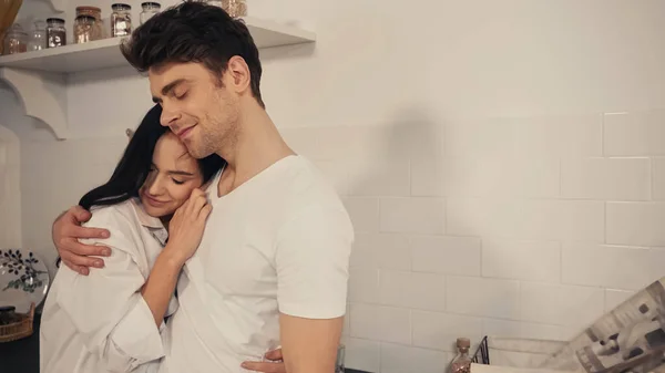 Sensual young woman in white shirt hugging happy boyfriend in t-shirt — Stock Photo