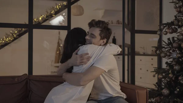 Homme heureux avec les yeux fermés et femme brune étreignant près décoré arbre de Noël — Photo de stock