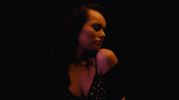 Mujer sexy en sujetador quitándose la blusa aislada en negro - foto de stock