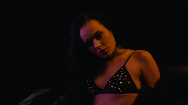 Sexy woman in bra looking at camera on black background — Stock Photo