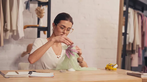 Couture en lunettes faisant robe sur petit mannequin près du mètre ruban sur la table — Photo de stock