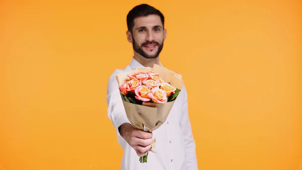 Happy bearded man holding bouquet of flowers isolated on yellow — Stock Photo