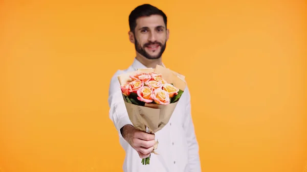 Homem barbudo feliz segurando buquê de flores isoladas no amarelo — Fotografia de Stock