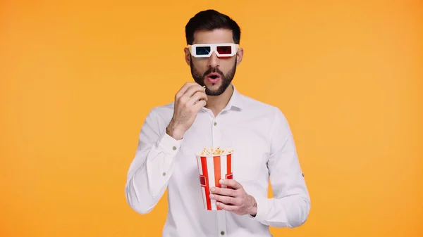 Barbudo hombre en 3d gafas celebración cubo y comer palomitas de maíz mientras ver película aislado en amarillo - foto de stock