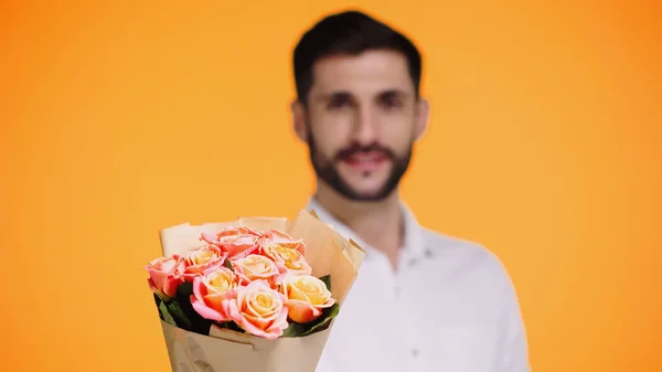 Cheerful and bearded man holding bouquet of flowers isolated on yellow — Stock Photo