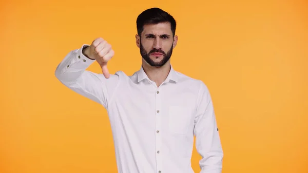 Dissatisfied man in white shirt showing thumb down isolated on yellow — Stock Photo