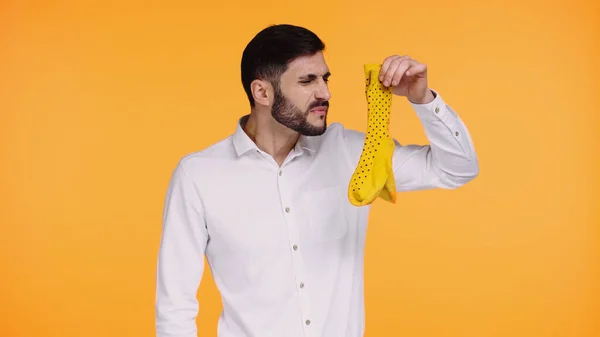 Hombre disgustado en camisa blanca sosteniendo calcetines apestosos aislados en amarillo - foto de stock