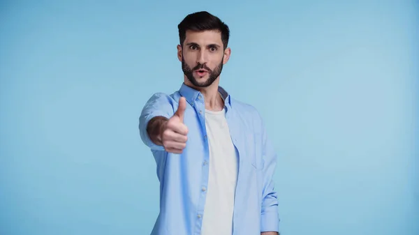 Bearded and excited man showing thumb up isolated on blue — Stock Photo