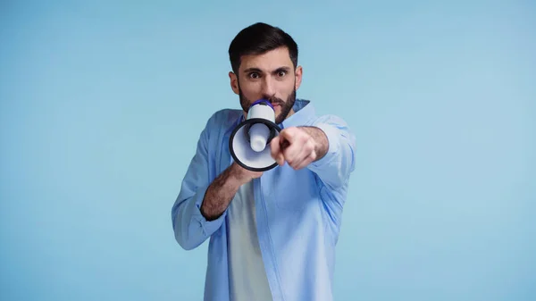 Hombre emocional haciendo anuncio en altavoz y señalando con el dedo aislado en azul - foto de stock