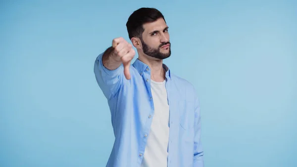 Decepcionado hombre en camisa mostrando el pulgar hacia abajo aislado en azul - foto de stock