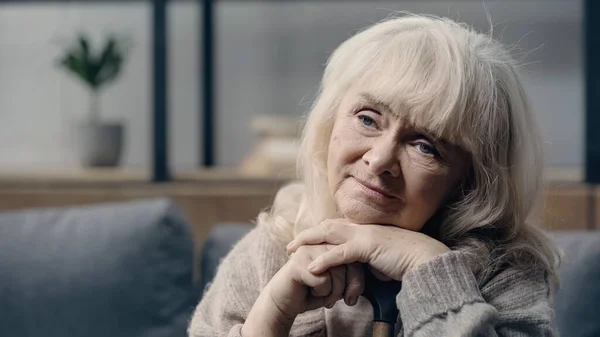 Depressed senior woman with dementia sitting with walking cane alone — Stock Photo