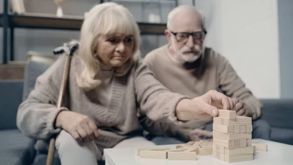 Pareja de ancianos con demencia jugando con bloques de madera en juego de torre juntos - foto de stock