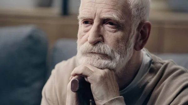 Bearded and sad senior man with dementia leaning on walking cane alone — Stock Photo