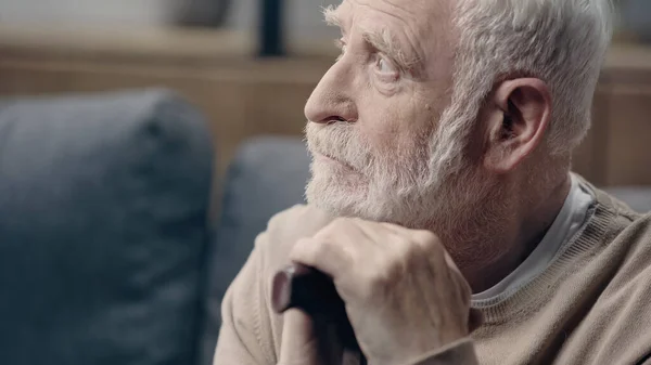 Upset senior man with dementia holding walking cane and looking away — Stock Photo