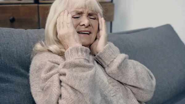 Seniorin mit Demenz hat Kopfschmerzen beim Sitzen auf Sofa — Stockfoto