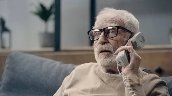 Senior man with dementia holding handset of retro telephone — Stock Photo