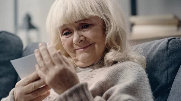 Щаслива старша жінка з деменцією дивиться на друковану фотографію — стокове фото