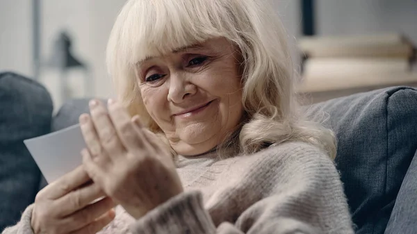 Happy senior woman with dementia looking at printed photograph — Stock Photo