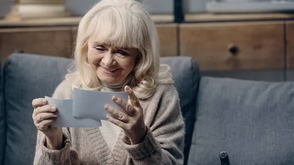 Щаслива старша жінка з деменцією тримає друковані фотографії вдома — стокове фото