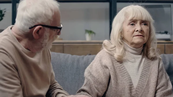 Senior man in eyeglasses looking at confused wife with dementia — Stock Photo