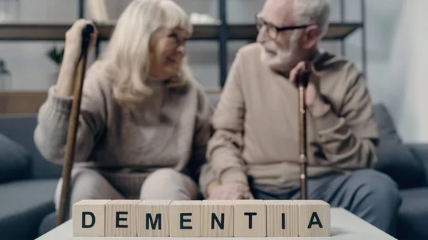 Focused wooden cubes with dementia lettering on table near senior couple — Stock Photo