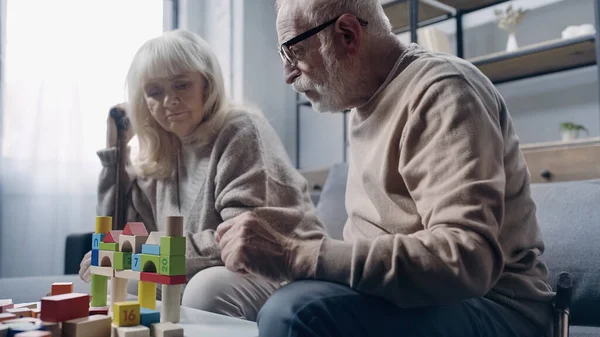 Couple retraité avec démence jouer avec des blocs de construction colorés sur la table — Photo de stock