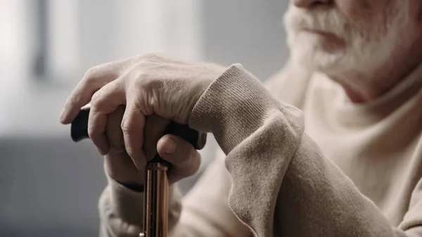 Cropped view of sad senior man with dementia holding walking cane — Stock Photo