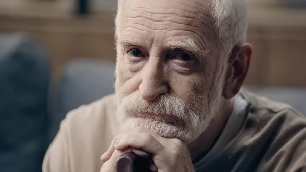 Triste uomo anziano con barba seduto con bastone da passeggio da solo — Foto stock