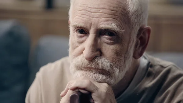 Sad senior man with beard sitting with walking cane alone — Stock Photo