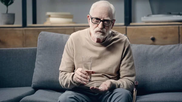 Uomo anziano con demenza in possesso di pillole e bicchiere d'acqua — Foto stock