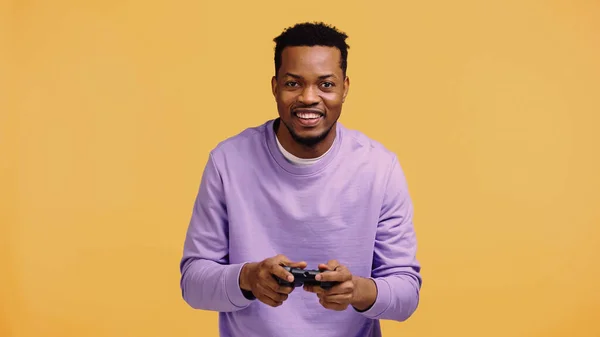 KYIV, UCRAINA - 22 NOVEMBRE 2019: allegro uomo afroamericano che gioca al videogioco isolato sul giallo — Foto stock