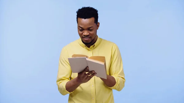 Smart afrikanisch-amerikanischer Mann in gelbem Hemd liest Buch isoliert auf blau — Stockfoto