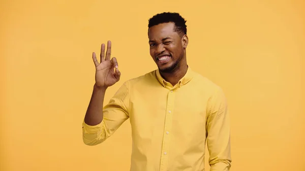 Alegre afro-americano homem na camisa mostrando ok gesto isolado no amarelo — Fotografia de Stock