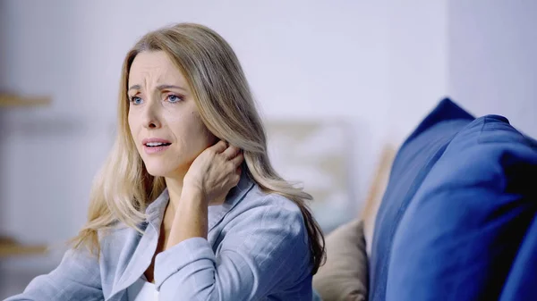 Besorgte blonde Frau schaut weg, während sie Schmerzen im Nacken hat — Stockfoto