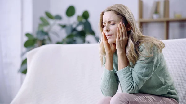 Femme triste avec les yeux fermés ayant la migraine tout en touchant la tête — Photo de stock