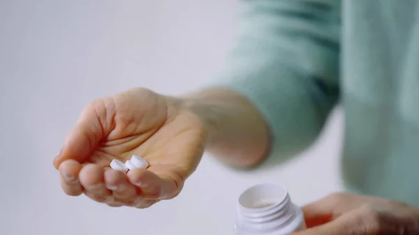 Vista parcial de la mujer sosteniendo píldoras y frasco en las manos — Stock Photo