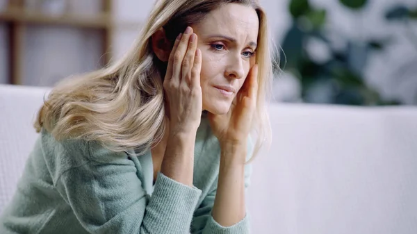 Traurige Frau mit Migräne beim Berühren des Kopfes im Wohnzimmer — Stockfoto