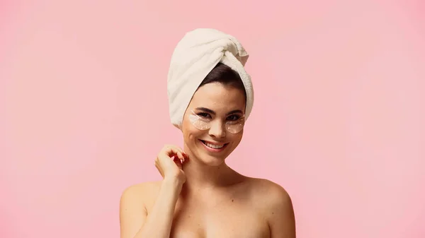 Happy young woman with bare shoulders and moisturizing eye patches isolated on pink — Stock Photo