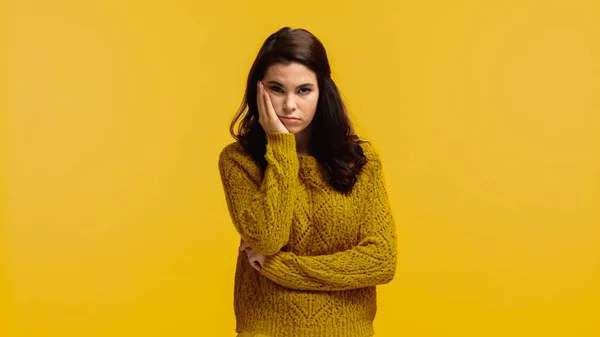 Junge und gelangweilte Frau im Pullover berührt Wange isoliert auf gelb — Stockfoto