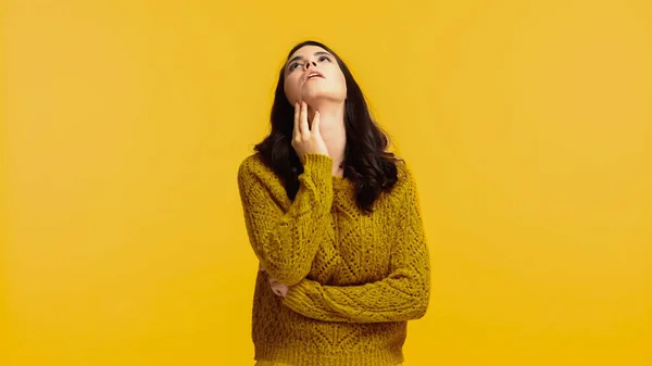 Bored young woman in sweater looking up isolated on yellow — Stock Photo