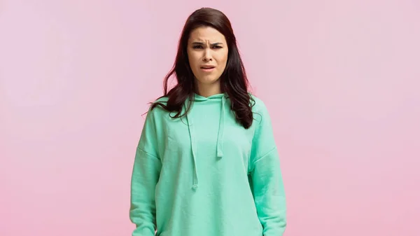 Upset young woman in turquoise hoodie looking at camera isolated on pink — Stock Photo