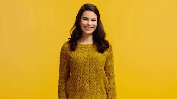 Cheerful and brunette woman in sweater looking at camera isolated on yellow — Stock Photo
