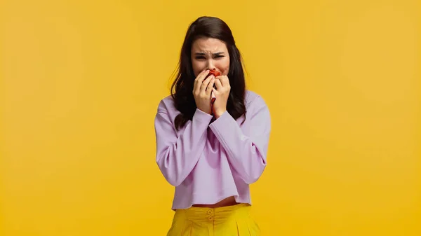 Chateado mulher em roxo sweatshirt cobrindo rosto enquanto chorando isolado no amarelo — Fotografia de Stock