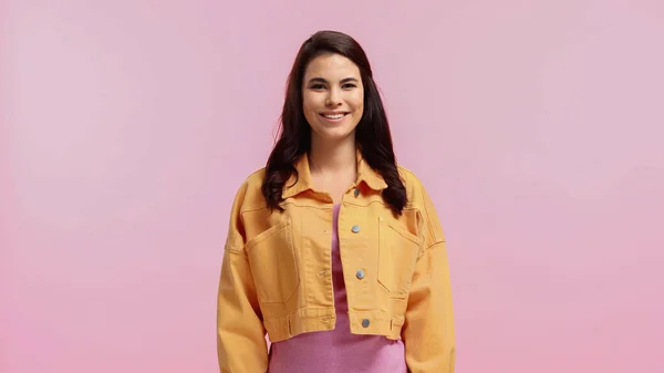 Glückliche junge Frau in orangefarbener Jeansjacke isoliert auf rosa — Stockfoto