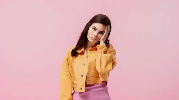 Bored young woman in orange denim jacket looking at camera isolated on pink — Stock Photo