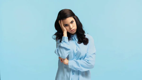 Displeased young woman in shirt touching head while puffing cheeks isolated on blue — Stock Photo