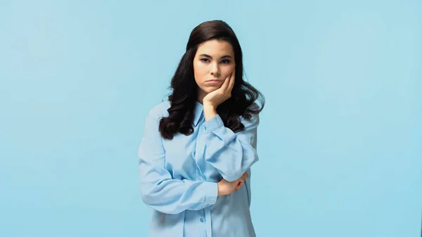 Skeptical young woman in shirt standing and looking at camera isolated on blue — Stock Photo