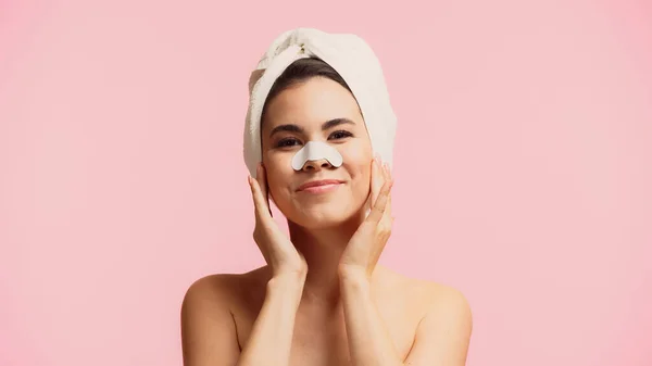 Happy young woman with patch on nose and towel on head smiling isolated on pink — Stock Photo