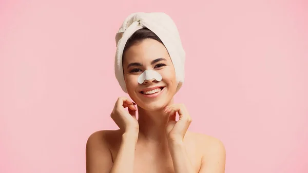Fröhliche junge Frau mit Handtuch auf dem Kopf und Pflaster auf der Nase lächelt isoliert auf rosa — Stockfoto